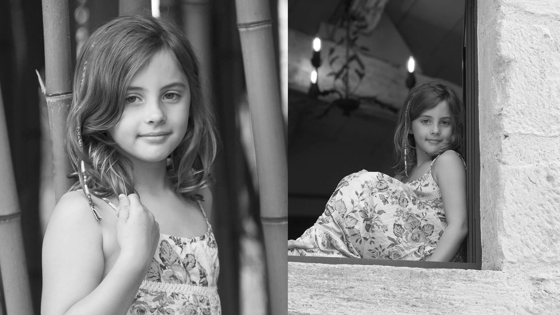 Portrait en noir et blanc d'une petite fille en robe fleurie, debout devant un fond de bambous.
