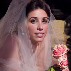 Portraits de mariée artistiques en couleur d'une mariée avec un bouquet de roses roses dans un intérieur historique en pierre